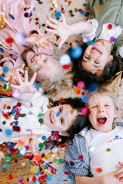 Kinder liegen auf Boden mit Konfetti